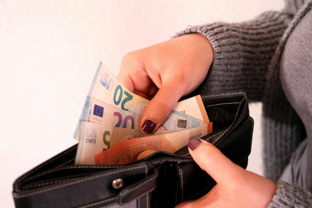 a woman is holding a wallet full of money